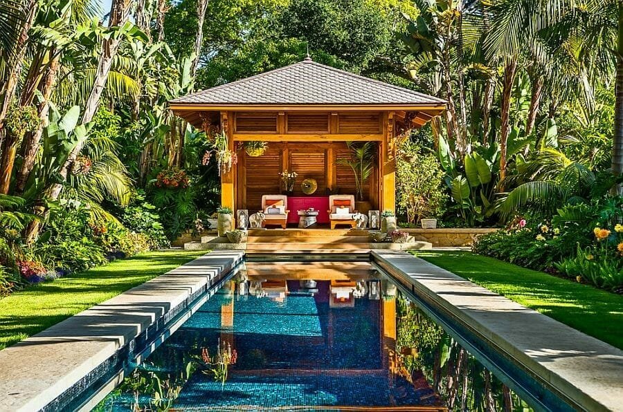 Covered backyard patio idea next to a pool with a lush garden